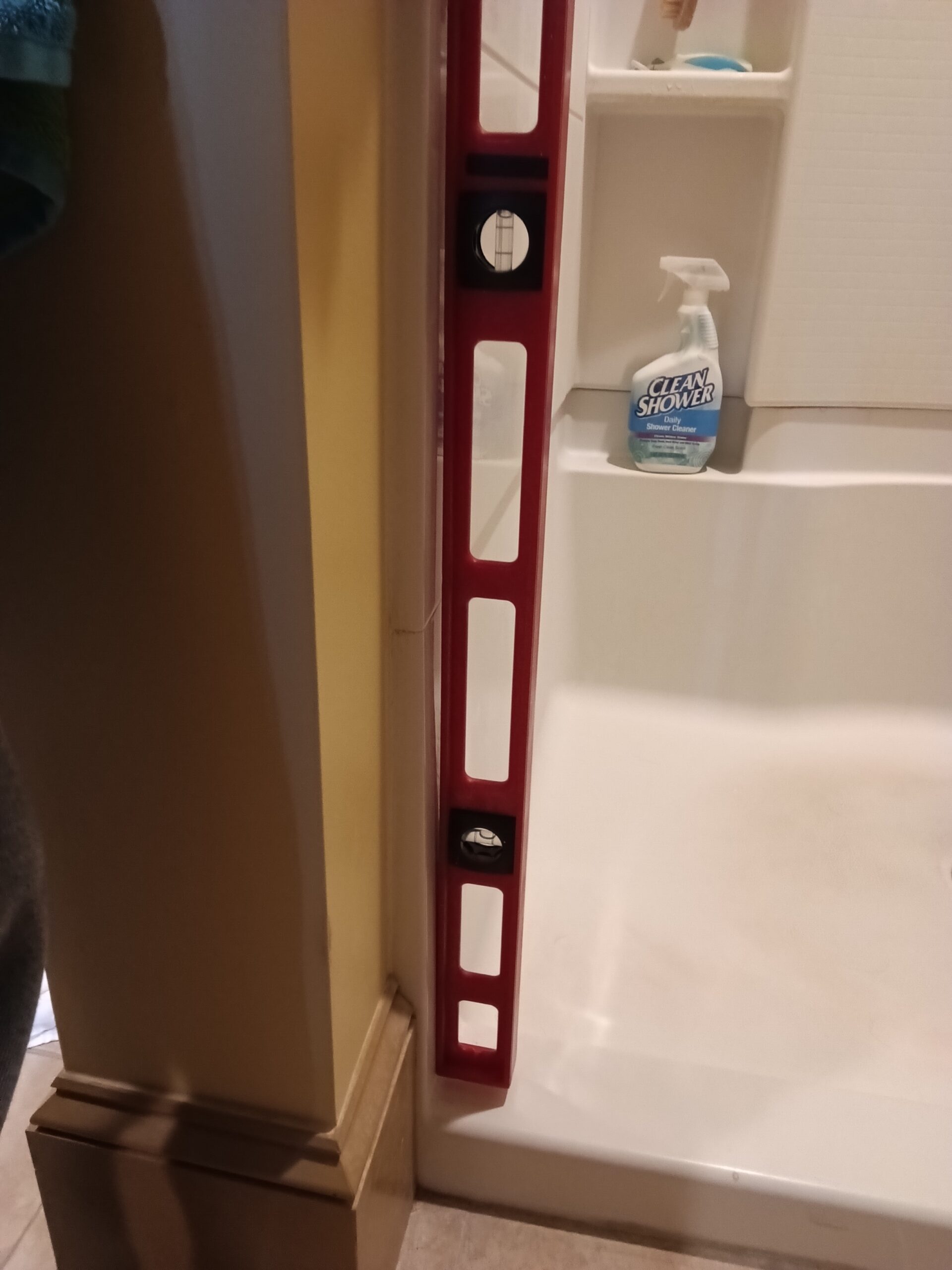 Level held against the shower opening during measurement of the uneven wall in West Chesterfield, NH.